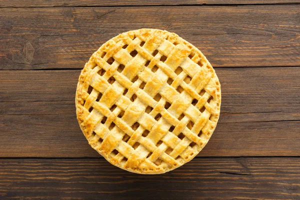 Домашній яблучний пиріг з решіткою зверху на коричневому дерев'яному фоні . — стокове фото