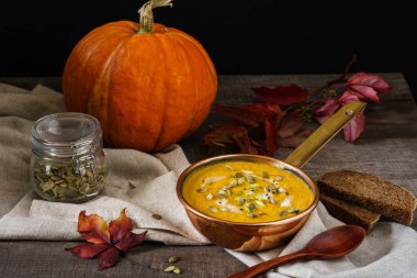 Ahşap bir masa üzerinde bakır tencerede kabak çorbası.
