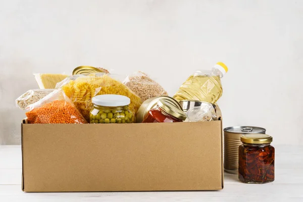 Varios alimentos enlatados, pasta y cereales en una caja de cartón . —  Fotos de Stock