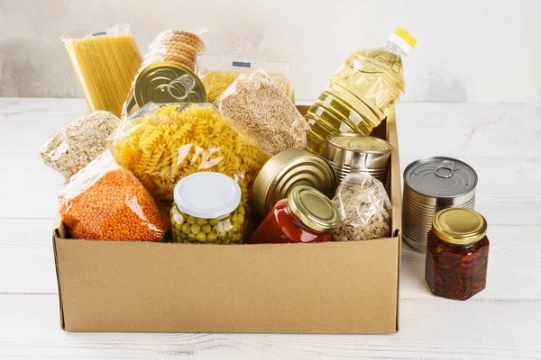 Vários alimentos enlatados, massas e cereais em uma caixa de papelão . — Fotografia de Stock