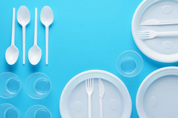 White plastic disposable tableware on blue background. — Stock Photo, Image