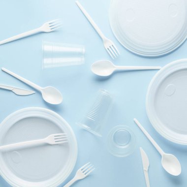 Mavi arka plan üzerinde çeşitli beyaz plastik tek kullanımlık sofra.