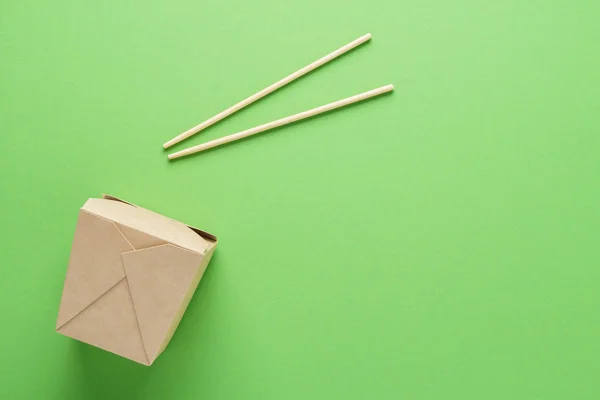 Recipiente de papel kraft e pauzinhos em fundo verde . — Fotografia de Stock