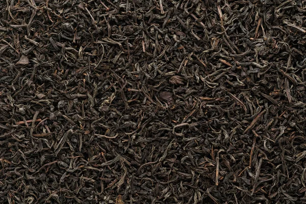 Trockene schwarze Teeblätter als Hintergrund, aufgenommen von oben. — Stockfoto