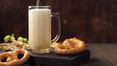 Lager birası bir kupaya akıyor. Koyu ahşap bir masada açık bira.