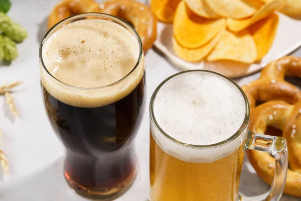 Two glasses of beer - light and dark with various snacks.