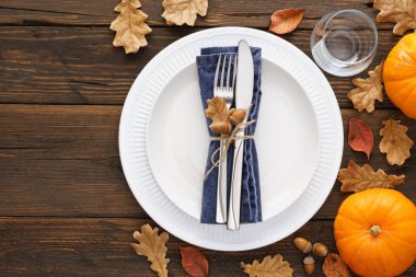 Şükran Günü sofrası beyaz tabaklar, süslü çatal bıçaklar, yapraklar ve balkabaklarıyla dolu. Mevsimlik catering konsepti. Boşluğu kopyala.