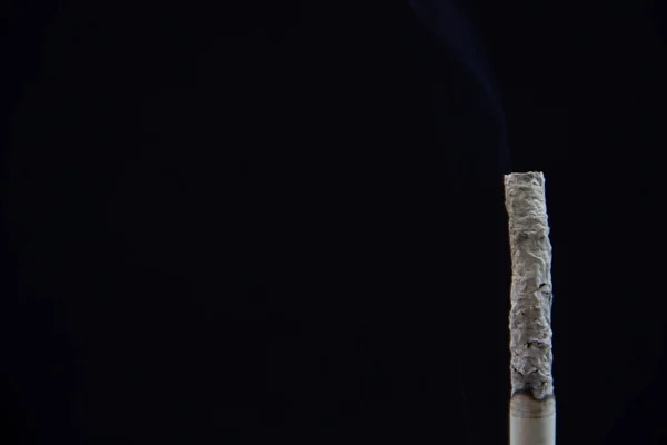 黒い背景にタバコを吸う — ストック写真