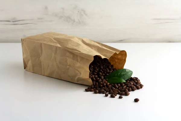 Kağıt paket, arka planda kahve çekirdekleri ile dolu.