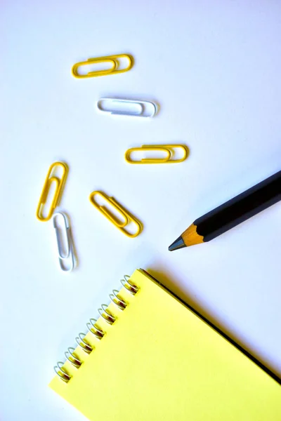 Black large pencil and Notepad and paper clips