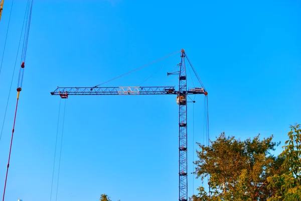 Yellow construction tower crane in the city against the sky