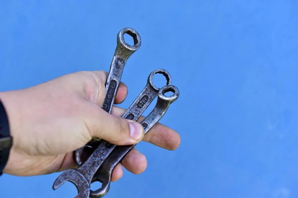 Carob cap wrench in hand on blue background