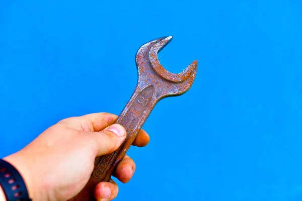 Iron horn cap wrenches in hand on a blue background
