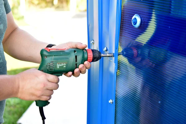 Working with a hand drill screwing bolts into the wall