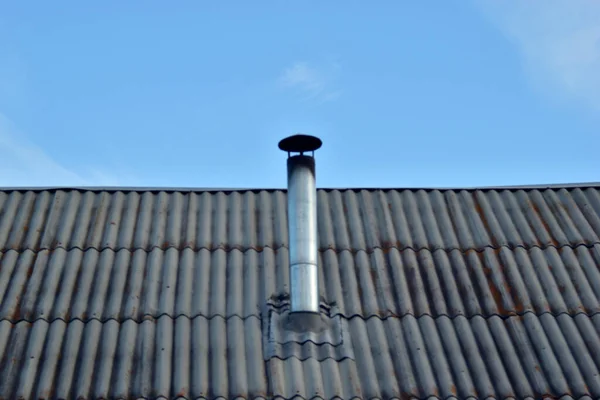 Iron chimney on the roof of the house with a visor