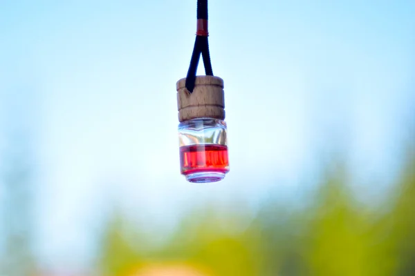 A bottle of red perfume for the car on a string