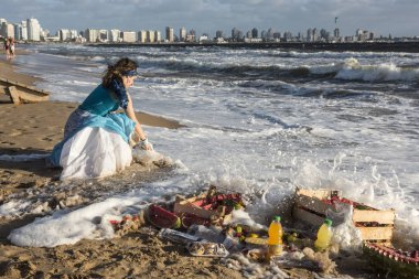 Maldonado, Uruguay - February 2, 2019: Woman from the Umbanda church brings fruits and sweets to Orisha Yemanja (Iemanja) on the Playa Mansa beach in Punta del Este clipart