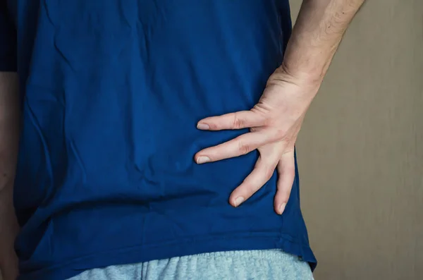 Un hombre sosteniendo su espalda. Dolor de espalda . —  Fotos de Stock