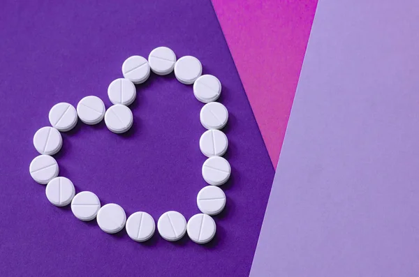 White heart pills on a colored background.