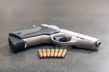 Handgun and Row of Bullets on Black Table