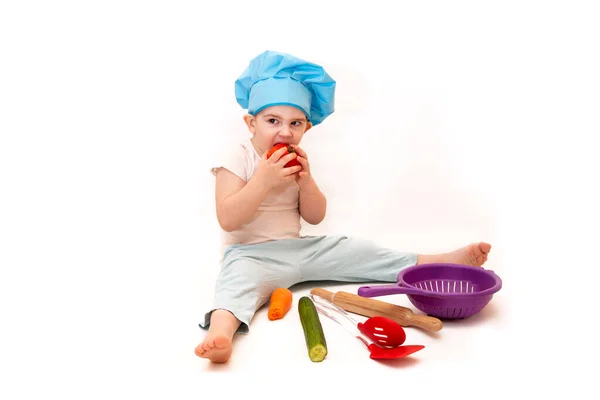A little boy in a chef\'s hat cooks in a toy kitchen  on a white background