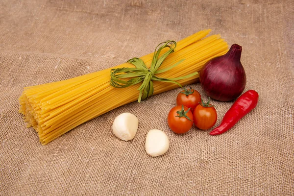 Raw Pasta with ingredients on linen or jute sacking or fabric.