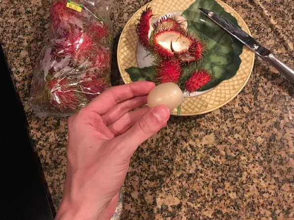 Man holding a rambutan fruit