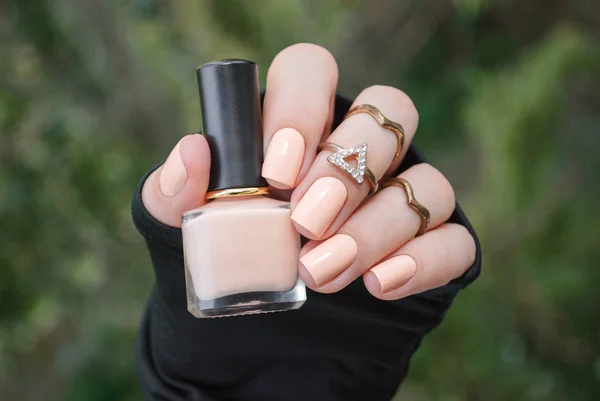 Manicura en manos femeninas con esmalte de uñas desnudo en el fondo verde . —  Fotos de Stock