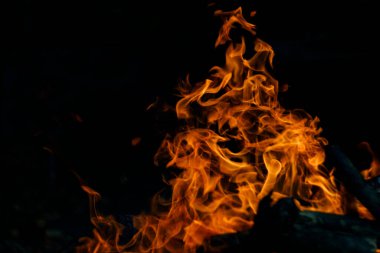 Siyah arka planda yangın. Ateş yandığında sonsuzluk şekilleri yaratır. Alevdeki portakal ve siyah arkaplan ilginç dokular yaratır. Cehennemin alevleri. Yakma gücü.