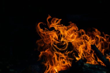 Siyah arka planda yangın. Ateş yandığında sonsuzluk şekilleri yaratır. Alevdeki portakal ve siyah arkaplan ilginç dokular yaratır. Cehennemin alevleri. Yakma gücü.
