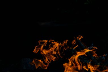 Siyah arka planda yangın. Ateş yandığında sonsuzluk şekilleri yaratır. Alevdeki portakal ve siyah arkaplan ilginç dokular yaratır. Cehennemin alevleri. Yakma gücü.