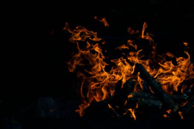 Siyah arka planda yangın. Ateş yandığında sonsuzluk şekilleri yaratır. Alevdeki portakal ve siyah arkaplan ilginç dokular yaratır. Cehennemin alevleri. Yakma gücü.