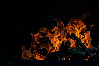 Siyah arka planda yangın. Ateş yandığında sonsuzluk şekilleri yaratır. Alevdeki portakal ve siyah arkaplan ilginç dokular yaratır. Cehennemin alevleri. Yakma gücü.