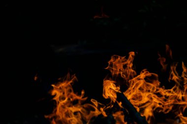 Siyah arka planda yangın. Ateş yandığında sonsuzluk şekilleri yaratır. Alevdeki portakal ve siyah arkaplan ilginç dokular yaratır. Cehennemin alevleri. Yakma gücü.