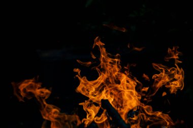 Siyah arka planda yangın. Ateş yandığında sonsuzluk şekilleri yaratır. Alevdeki portakal ve siyah arkaplan ilginç dokular yaratır. Cehennemin alevleri. Yakma gücü.