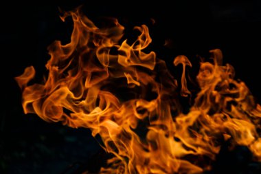 Siyah arka planda yangın. Ateş yandığında sonsuzluk şekilleri yaratır. Alevdeki portakal ve siyah arkaplan ilginç dokular yaratır. Cehennemin alevleri. Yakma gücü.