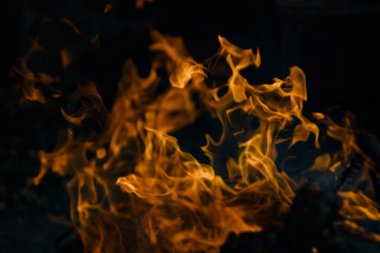 Siyah arka planda yangın. Ateş yandığında sonsuzluk şekilleri yaratır. Alevdeki portakal ve siyah arkaplan ilginç dokular yaratır. Cehennemin alevleri. Yakma gücü.