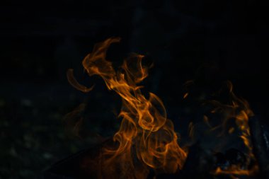 Siyah arka planda yangın. Ateş yandığında sonsuzluk şekilleri yaratır. Alevdeki portakal ve siyah arkaplan ilginç dokular yaratır. Cehennemin alevleri. Yakma gücü.