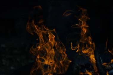 Siyah arka planda yangın. Ateş yandığında sonsuzluk şekilleri yaratır. Alevdeki portakal ve siyah arkaplan ilginç dokular yaratır. Cehennemin alevleri. Yakma gücü.