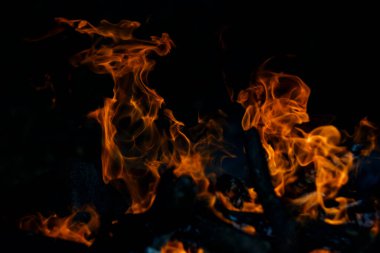 Siyah arka planda yangın. Ateş yandığında sonsuzluk şekilleri yaratır. Alevdeki portakal ve siyah arkaplan ilginç dokular yaratır. Cehennemin alevleri. Yakma gücü.