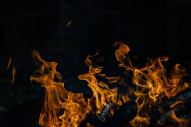 Siyah arka planda yangın. Ateş yandığında sonsuzluk şekilleri yaratır. Alevdeki portakal ve siyah arkaplan ilginç dokular yaratır. Cehennemin alevleri. Yakma gücü.