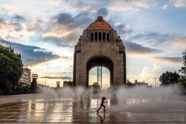 Mexico City, Meksika - 4 Kasım 2016: Meksika Devrimi (Monumento la Revoluciön) - Mexico City, Meksika için anıt önünde su çeşme ile oynayan kız