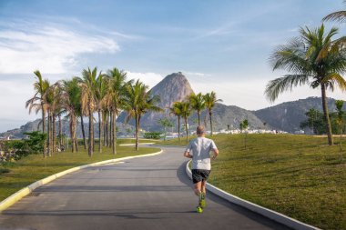 Rio de Janeiro, Brazil - Oct 25, 2017: Man running at Marina da Gloria track and Sugar Loaf Mountain on background - Rio de Janeiro, Brazil clipart
