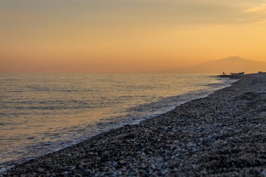 Günbatımı üzerinde bir Akdeniz beach, İyon Denizi Mount Etna Yanardağı ile arka planda - Bova Marina, Calabria, İtalya