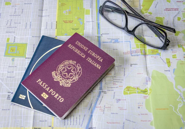 Planning a trip - Italian and Brazilian passports on city map with glasses