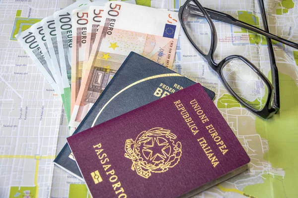 Planning a trip - Italian and Brazilian passport on city map with euro bills money and glasses
