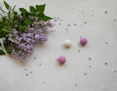 Kozmetik düz bir buket çiçekler Lila ile yatıyordu. Gri beton arka planda Spa El yapımı öfkeli bombalar.