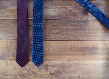 Üst manzara mavi ve menekşe bezelyeli kravatlar ve kahverengi ahşap arka planda bir şerit. Üst düzey erkek aksesuarları.