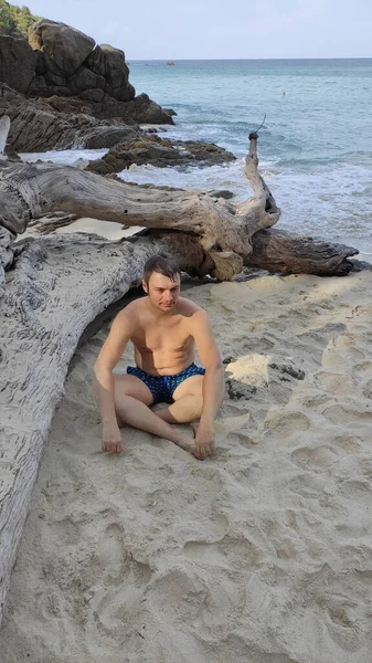 Młody Mężczyzna Spodenkach Plażowych Siedzi Piasku Opalając Się Medytując Odpoczywający — Zdjęcie stockowe