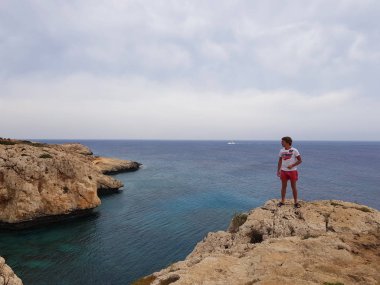 Deniz, Kıbrıs, Protaras, Mayıs 2018 görüntüleyin. Güzel mavi deniz. Kayalar ve dağlar. Bu manzara karşısında gelen nefes alıyor. Bir adam bir kaya üzerinde sırtında ve şu güzelliğe bakar
